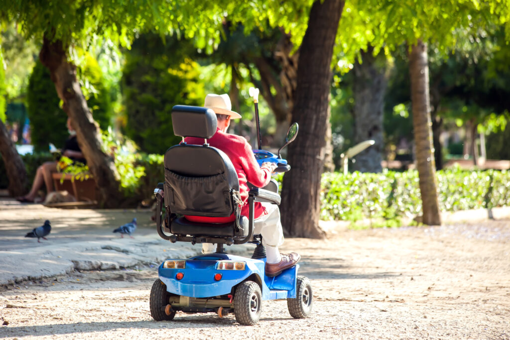 Disabled senior man using electric wheelchair in the park.